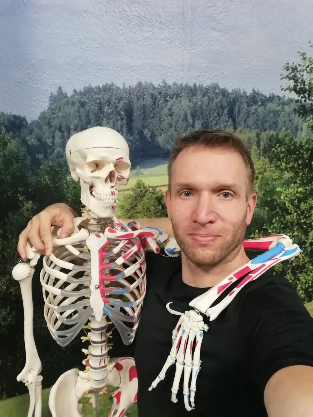 Filip Morkus stojí venku vedle anatomického modelu kostry s barevně vyznačenými svaly